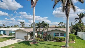A residential area with houses, palm trees, and a clear sky. - Canal-Front Home w/ Boat Lift in Cape Coral! (Cape Coral)