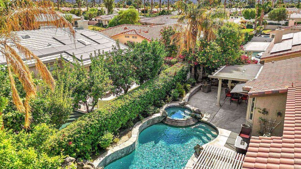 Un quartier résidentiel doté d’une piscine entourée d’une végétation luxuriante et d’un espace patio.