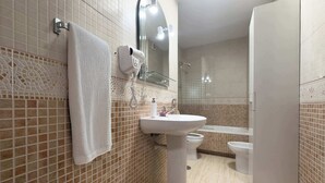 A bathroom with a tiled floor, a sink, a toilet, and a bathtub.