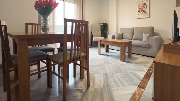 A living room with a wooden dining table, chairs, a sofa, and a coffee table.