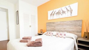Ein geräumiges Schlafzimmer mit einem großen Bett, einer Kopfteil und einem Wandbild von Giraffen.