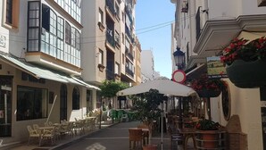 A narrow street with outdoor seating, a café, and a building with a sign reading "El Rincon Toso". - Cristamar Center and Beach Penthouse (Estepona)
