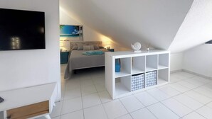 A modern bedroom with a bed, a TV, a painting, and a white console with storage. - Cristamar Center and Beach Penthouse (Estepona)