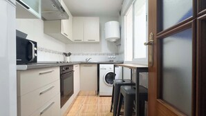 Une cuisine compacte équipée d’un four à micro-ondes, d’un four, d’un évier et d’un lave-linge.