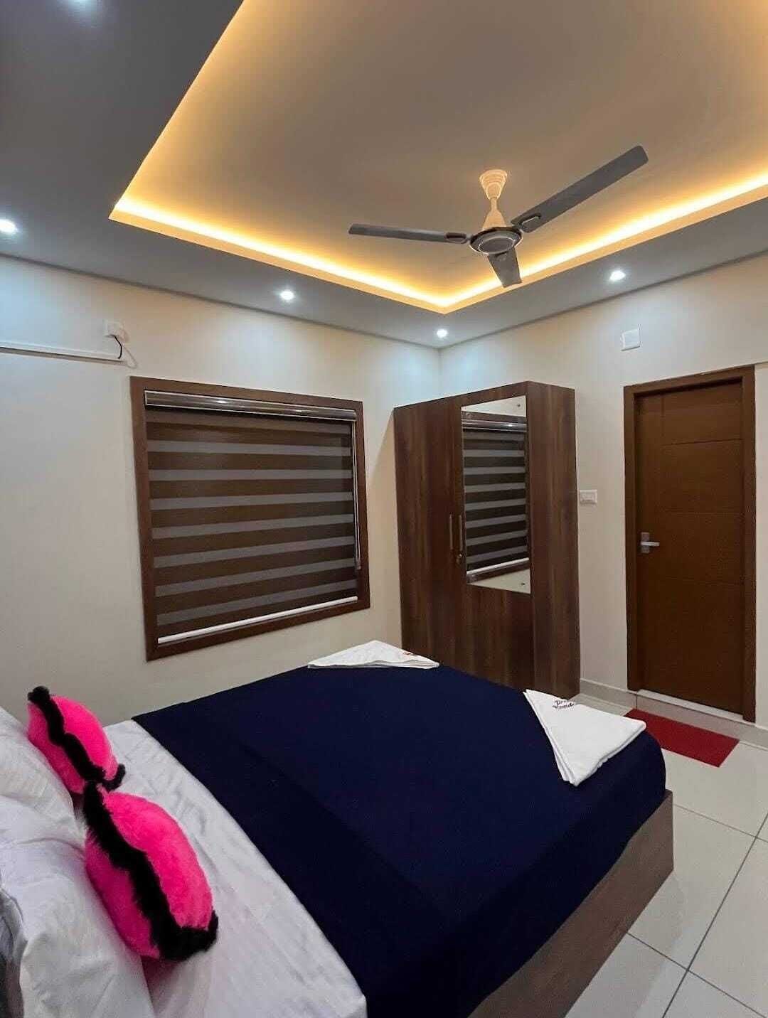 A bedroom with a bed, a ceiling fan, a wardrobe, and a door.