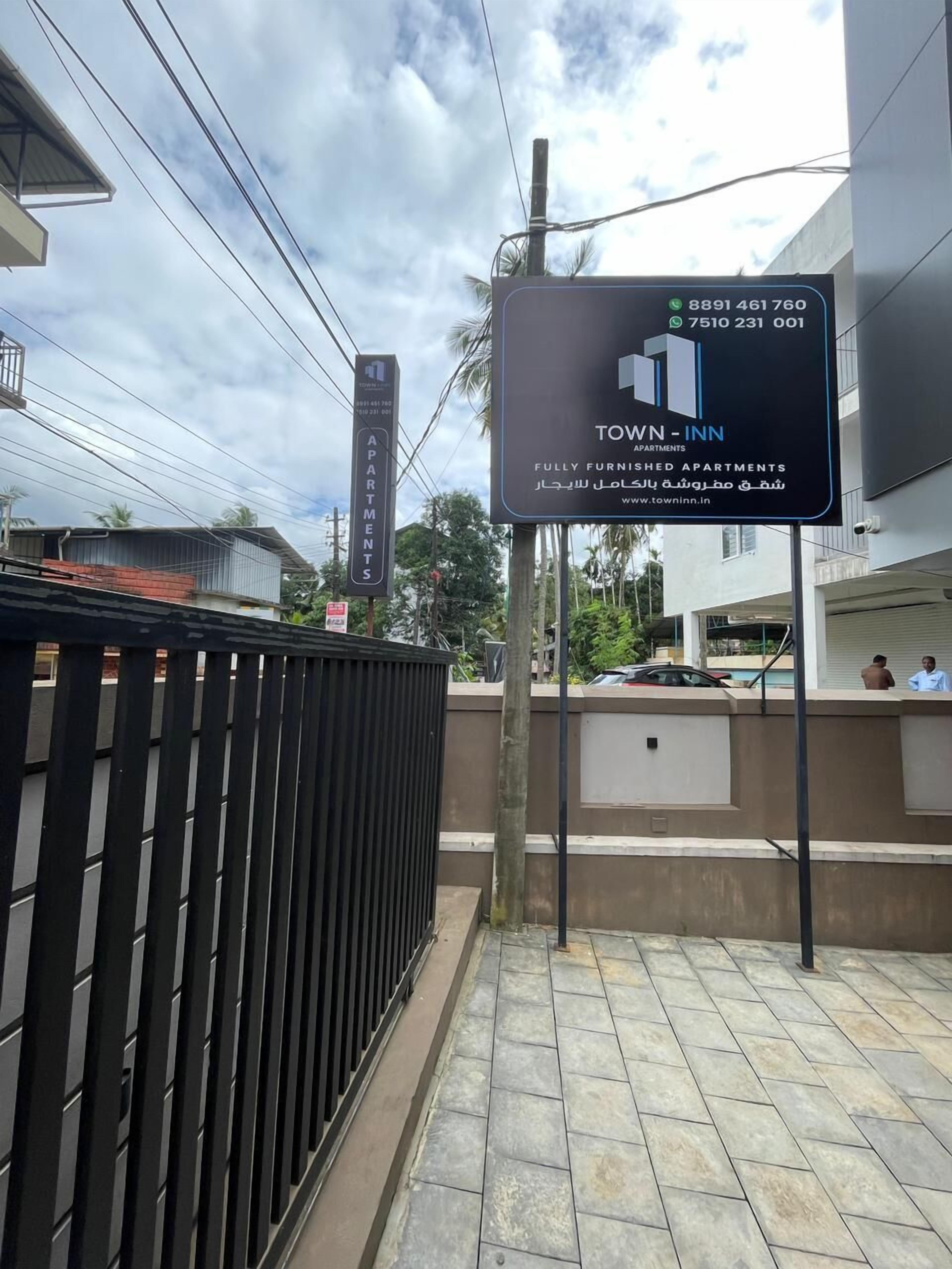 A sign for Town Inn apartments with contact numbers and a website URL.