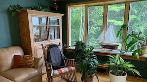 Un salon chaleureux avec un meuble en bois, un canapé en cuir, un fauteuil à bascule et plusieurs plantes en pot.