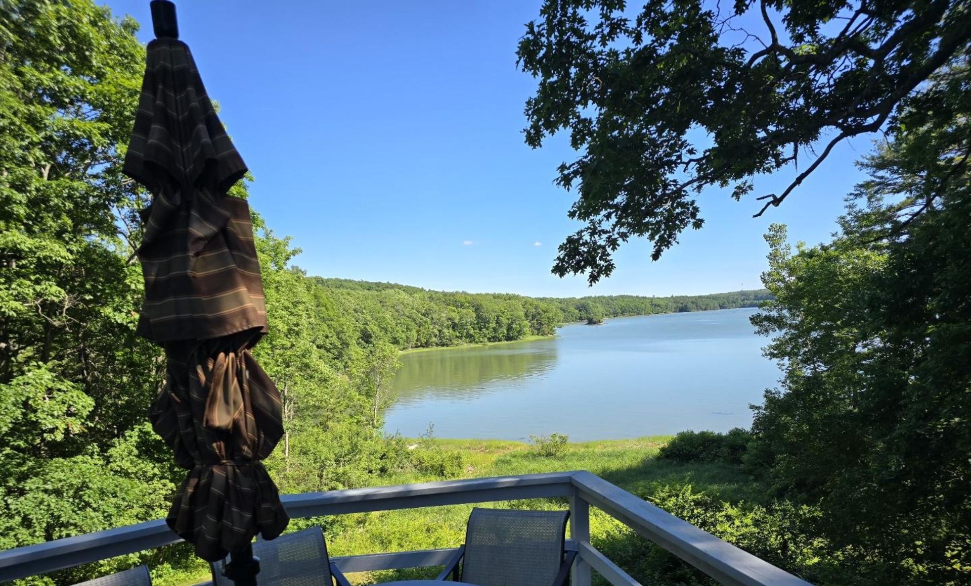 A deck with a view of a lake surrounded by trees.