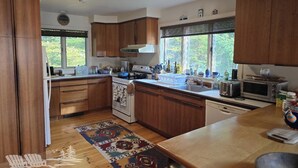 Une cuisine moderne avec des meubles en bois, un îlot central et une grande fenêtre qui laisse entrer la lumière naturelle.