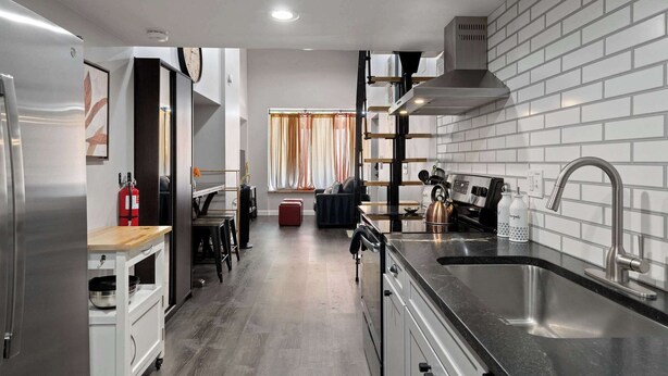 A modern kitchen with a stainless steel refrigerator, a built-in oven, and a black countertop sink. - Updated Loft in a Convenient Area! (Wheat Ridge)