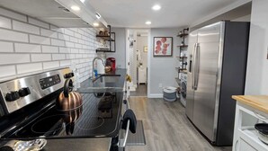 A modern kitchen with a stainless steel refrigerator, a kettle on the stove, and a sink. - Updated Loft in a Convenient Area! (Wheat Ridge)