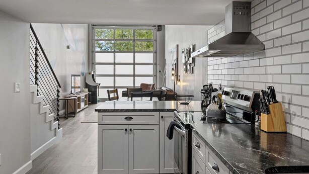 A modern kitchen with a central island, stainless steel appliances, and a large window providing natural light. - Industrial-Chic Loft with King Bed Close to Shops! (Wheat Ridge)