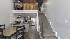 A modern kitchen with a dining area, a staircase, and a loft space. - Industrial-Chic Loft with King Bed Close to Shops! (Wheat Ridge)