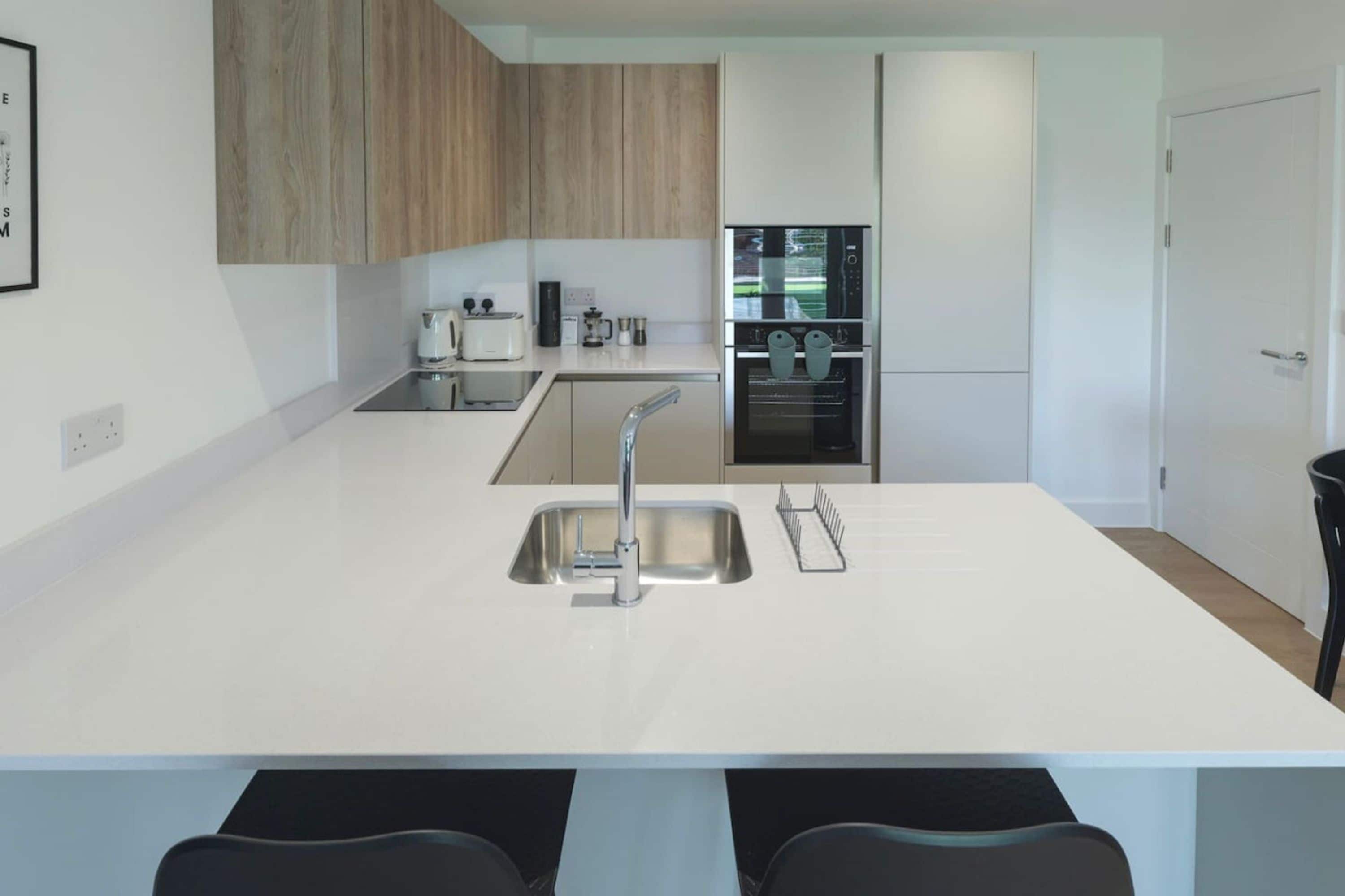 A modern kitchen with a central island, stainless steel appliances, and wooden cabinetry.