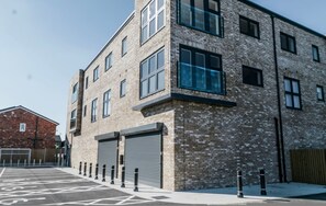 Un immeuble à plusieurs étages, doté d’une façade en briques, de grandes fenêtres et d’une porte de garage.