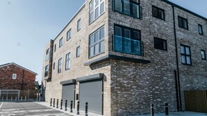A multi-story building with a brick facade, large windows, and a garage door.