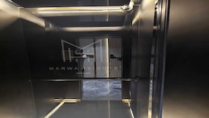 An elevator interior with a reflective floor and a logo on the wall.