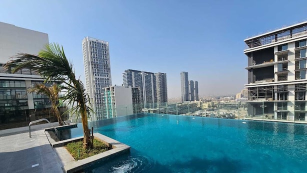 A rooftop infinity pool with a city view, surrounded by modern buildings.