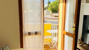 A room with a sofa, a dining table with chairs, and a sliding glass door leading outside. - Apartment in beachfront residence (Alghero)