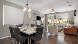 Un salon moderne avec un coin repas, comprenant une grande table à manger, des sièges confortables et un ventilateur de plafond.