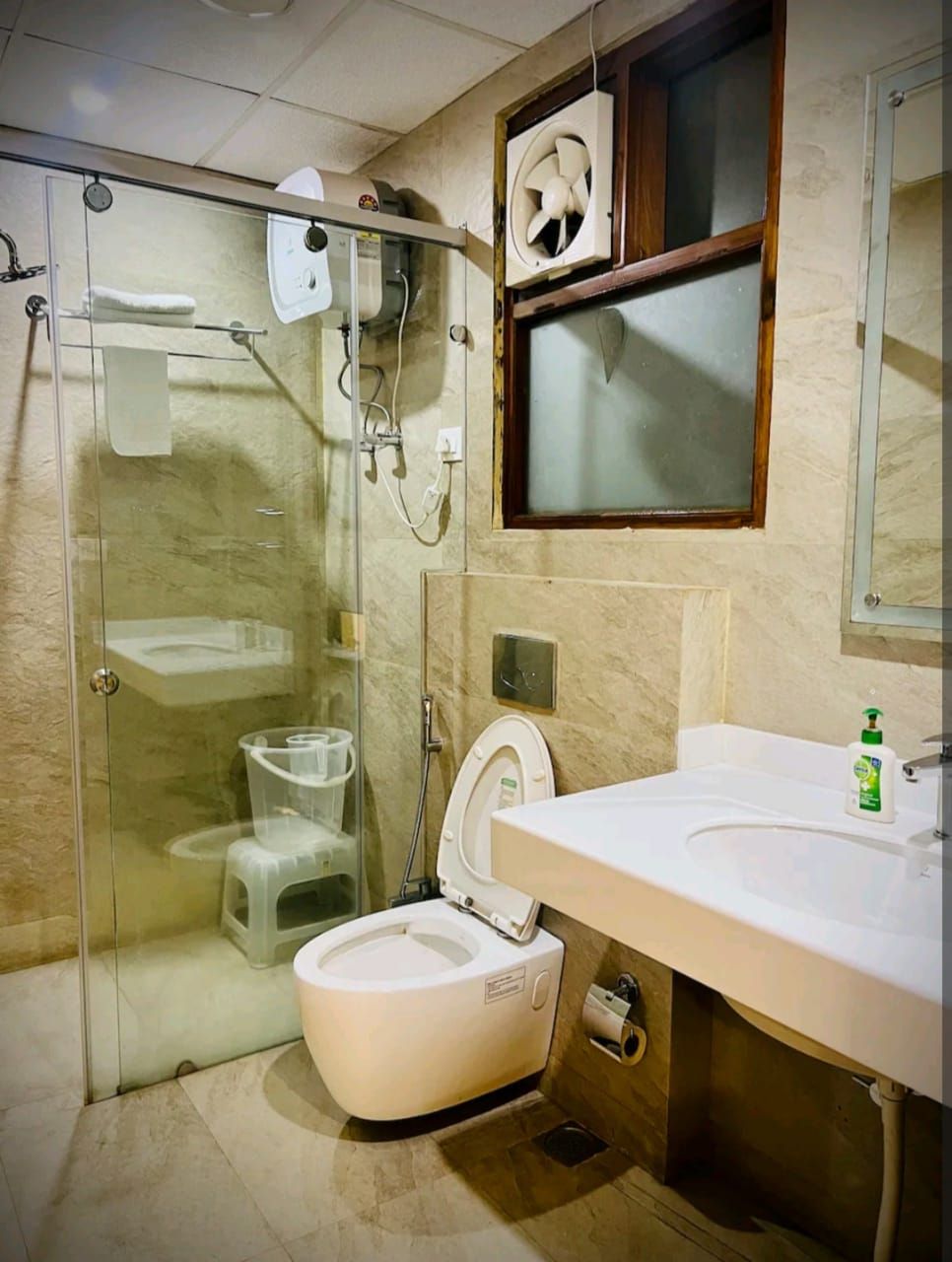 A compact bathroom with a glass-enclosed shower, a toilet, and a sink with a mirror above it.