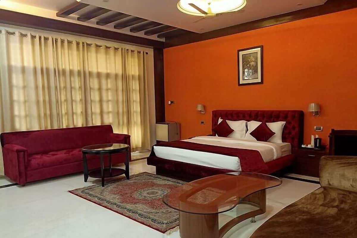 Une chambre d’hôtel avec un lit, un canapé rouge, une petite table et une chaise.