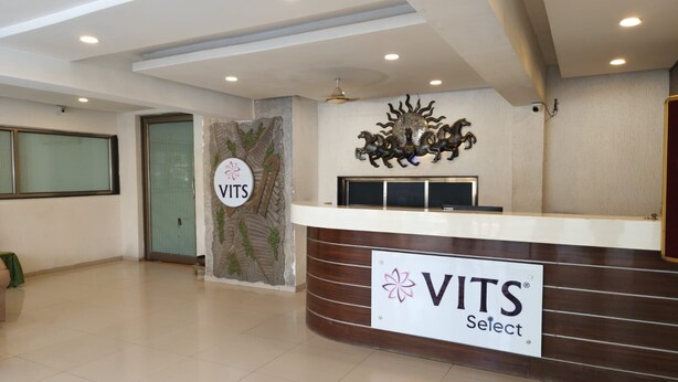Una zona d'entrada amb un cartell de VITS Select, una taula d'informació, una paret decorativa i un ventilador de sostre.