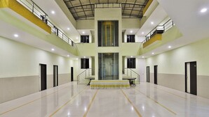 Un atrium espaiós de diversos nivells amb una escala central, diverses portes i un sòl polit.