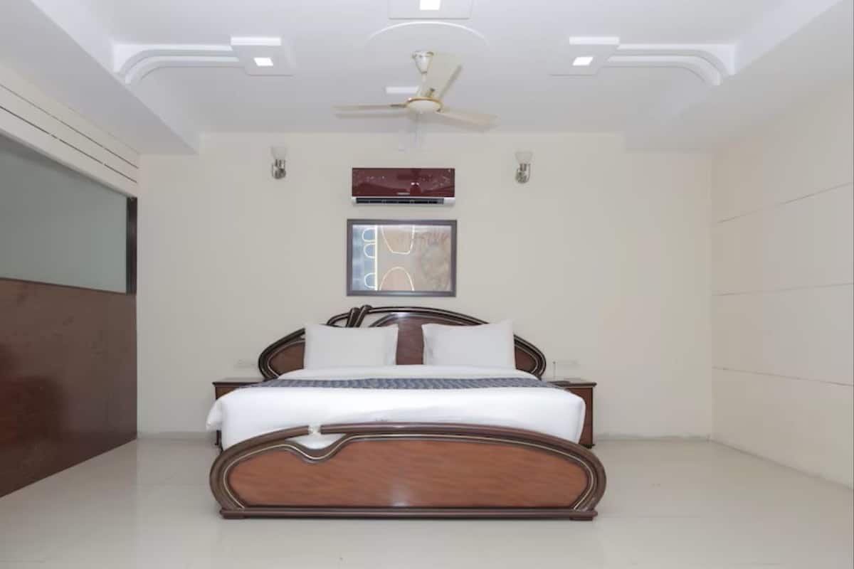 A modern bedroom with a wooden bed, a ceiling fan, recessed lighting, and a framed artwork on the wall.