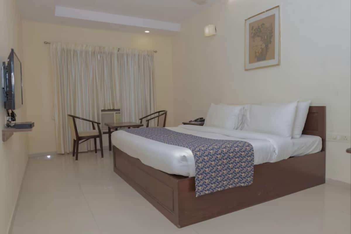 A hotel room with a large bed, a desk, and a chair.
