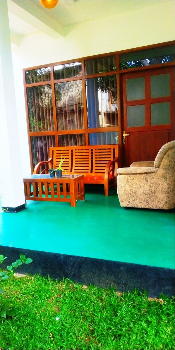 Una habitación con piso verde, muebles de madera y un ventanal con vista a árboles.