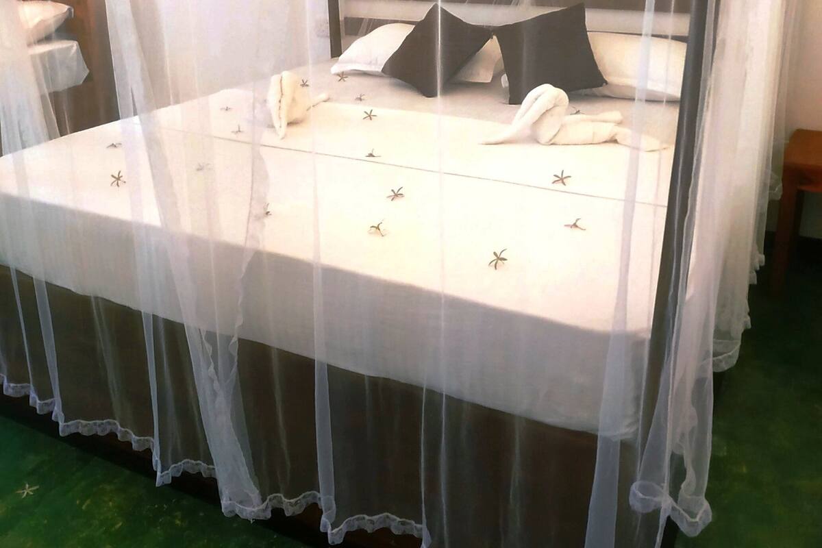 Una cama con dosel, almohadas y colcha con estampado de estrellas.