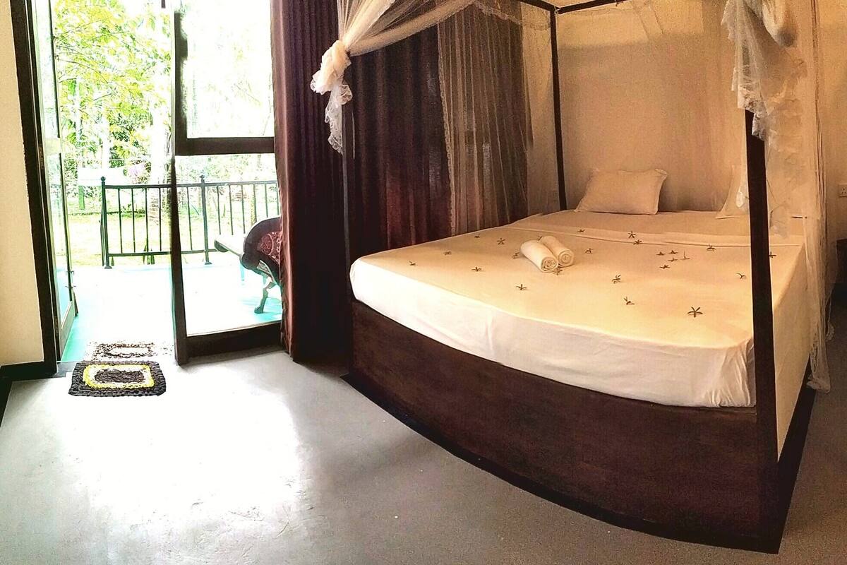 Una habitación con dos camas, cada una con dosel. Hay una mesita y una silla cerca de la ventana.