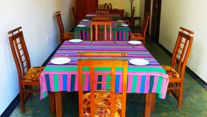 A dining area with a long table set for six, surrounded by wooden chairs with cushioned seats.