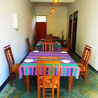 Comedor con una mesa larga dispuesta para seis comensales, rodeada de sillas de madera con asientos acolchados.