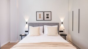 A modern bedroom with a large bed, two bedside tables, and two wall-mounted light fixtures. - Lovely 3BR Apartment in Pangrati (Kesariani)