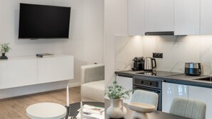 A modern kitchen with a flat-screen TV mounted above the counter, a coffee maker, and a kettle. - Lovely 3BR Apartment in Pangrati (Kesariani)
