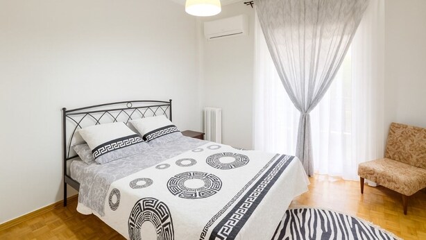 A bedroom with a bed, a chair, a hanging light, and a window with curtains. - Sunny Dream House (Agios Ioannis Rentis)