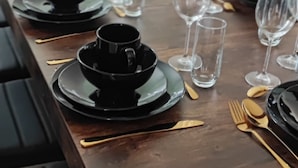 A dining table set with black and gold tableware, including plates, bowls, and cutlery. - 12th century Manoir des Templiers, with heated swimming pool, jacuzzi, mini golf course  (Trancault)