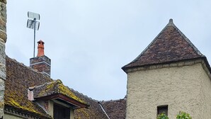 A rustic building with a stone facade, a tiled roof, and a small garden area with a grill and outdoor seating. - 12th century Manoir des Templiers, with heated swimming pool, jacuzzi, mini golf course  (Trancault)