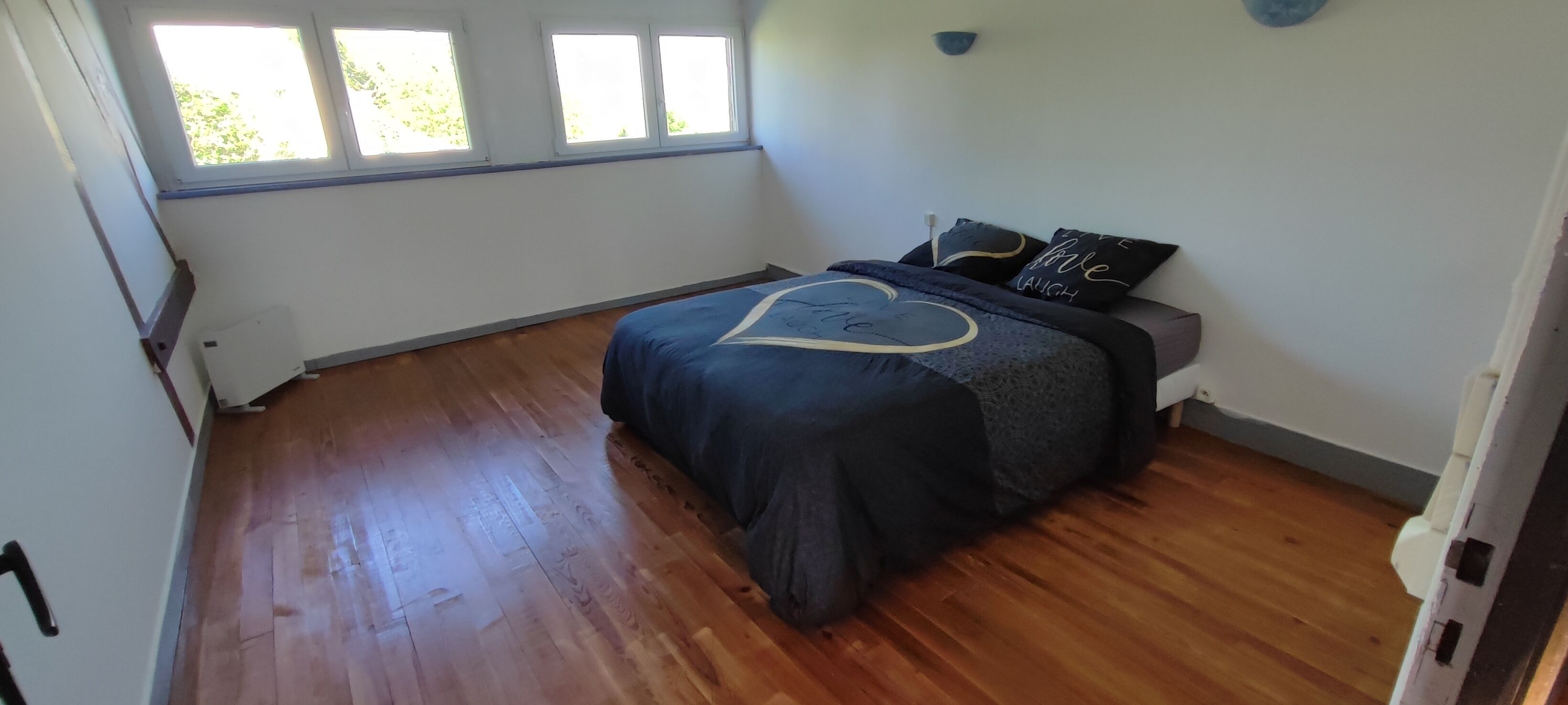A bedroom with a bed, a window, and a radiator.