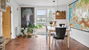 Un coin repas avec une table en bois, des chaises noires, une grande carte accrochée au mur et une plante en pot.