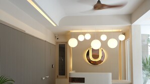 A modern reception area with a ceiling fan, a circular light fixture, and a reception desk. - Urban Room Samed (Rayong)