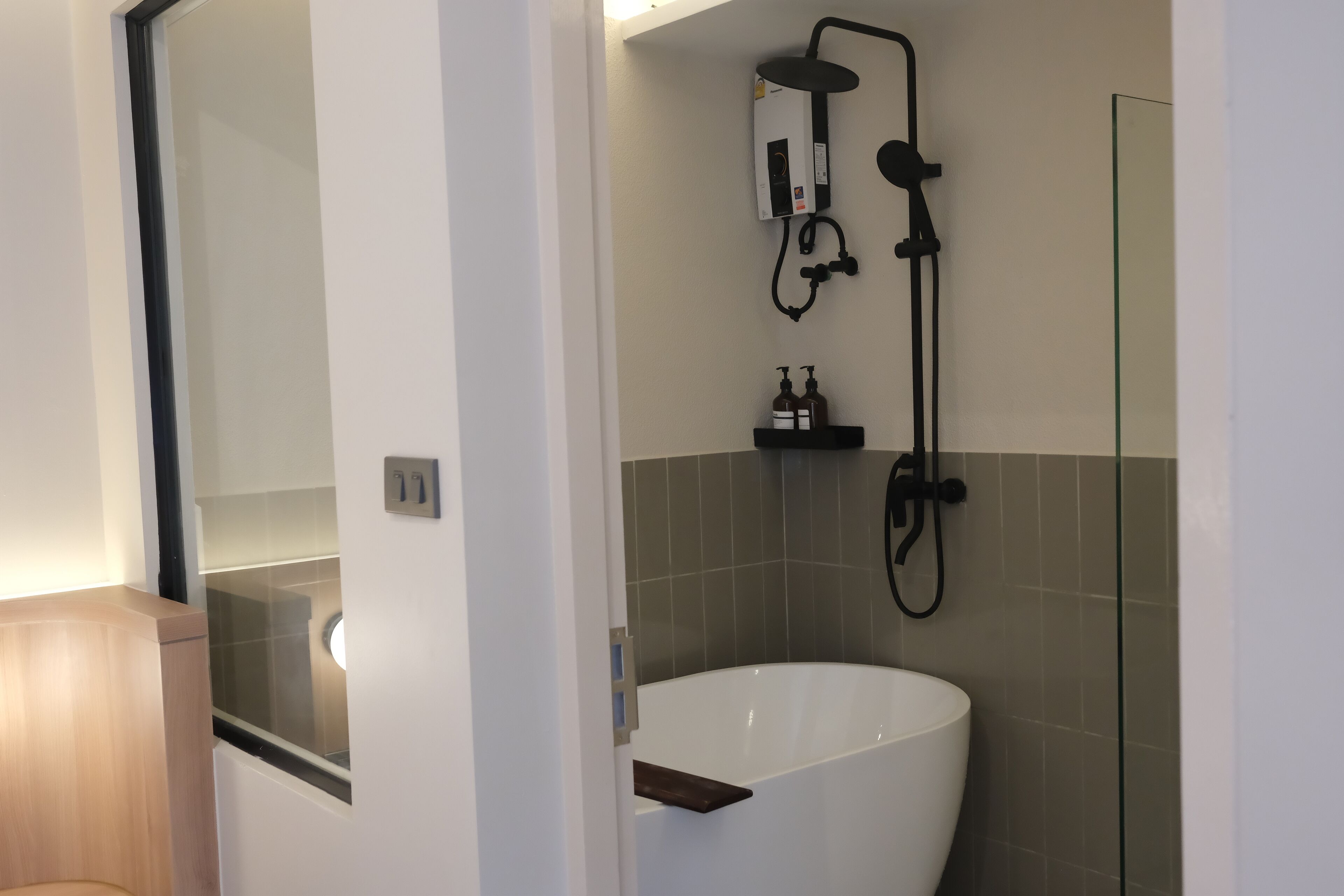 Un baño moderno con una bañera independiente, cabina de ducha con mampara de cristal y un banco de madera.