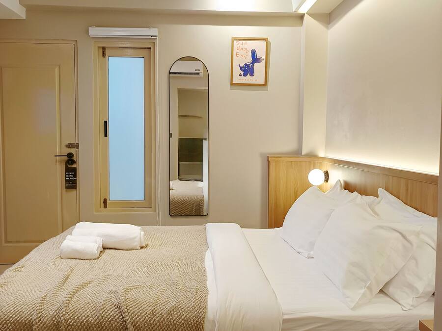Una habitación de hotel con una cama, una mesita de noche, un espejo y una puerta.