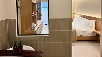 Un baño moderno con un espejo grande, una bañera y una zona de ducha.