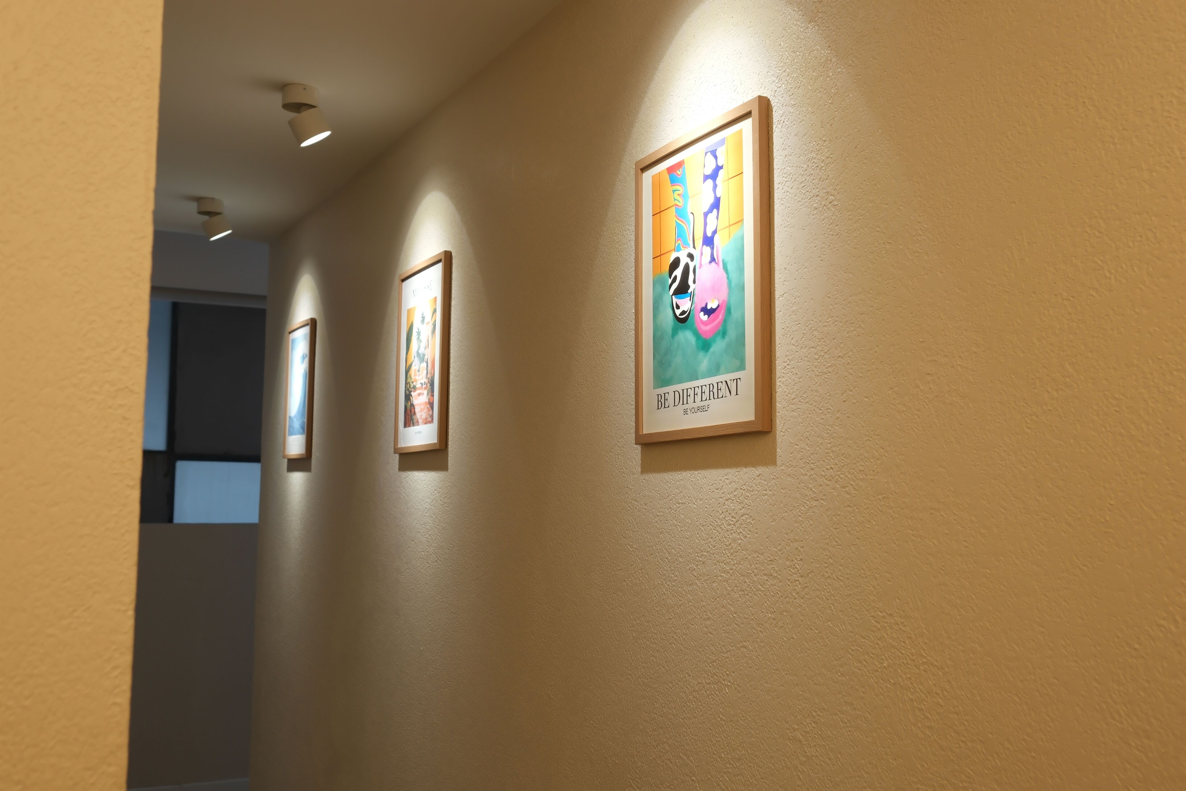 A hallway with framed artwork on the walls and recessed lighting.
