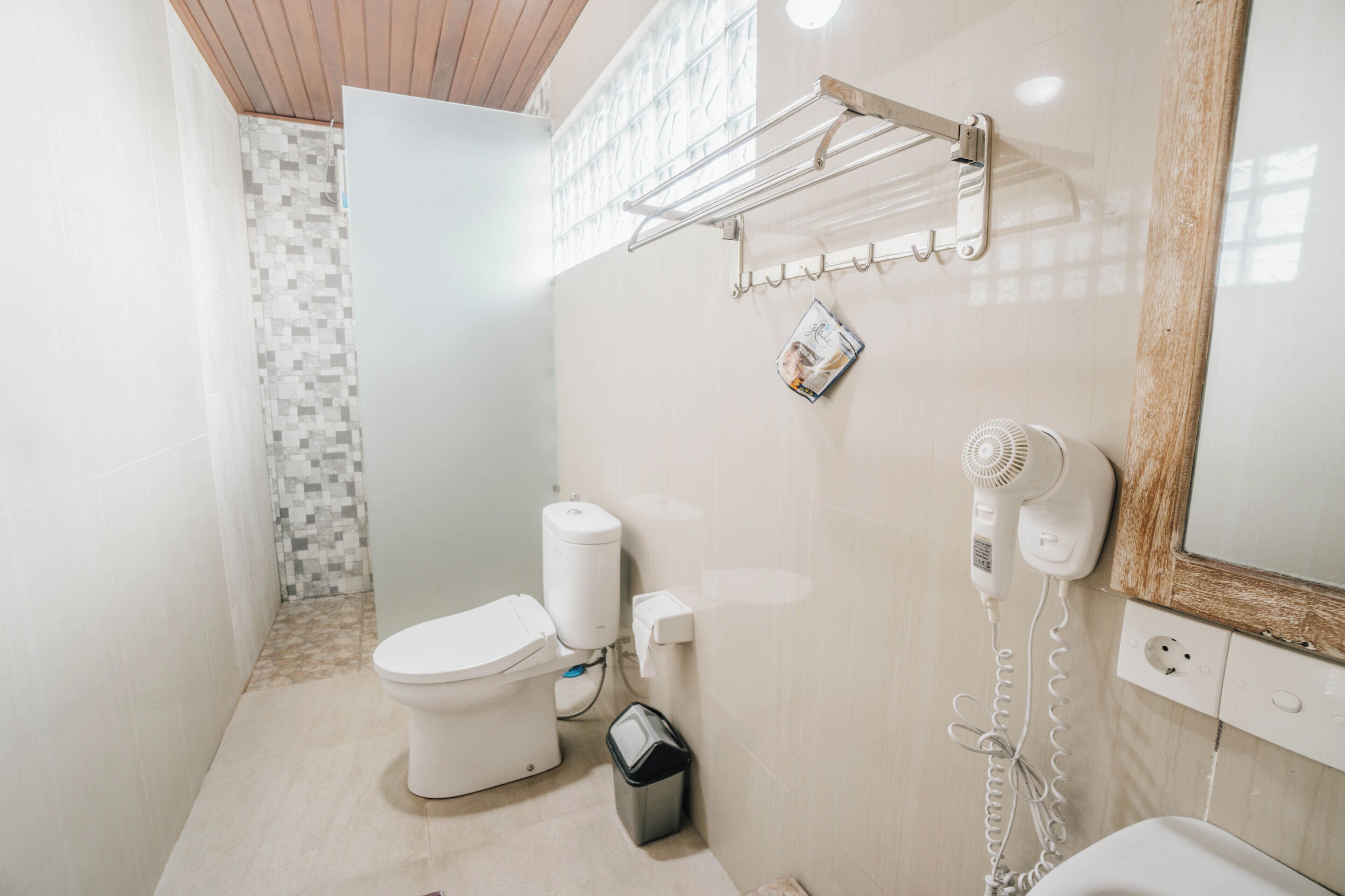 A compact bathroom with a toilet, a hand dryer, and a towel rack.