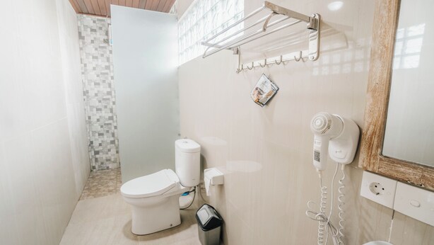 A compact bathroom with a toilet, a hand dryer, and a towel rack. - Ganesha Villa (Ubud)
