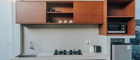 A kitchen with wooden cabinets, a gas stove, a microwave, and a refrigerator.